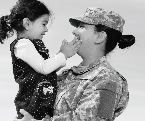 Small girl affectionately smiles at military worker